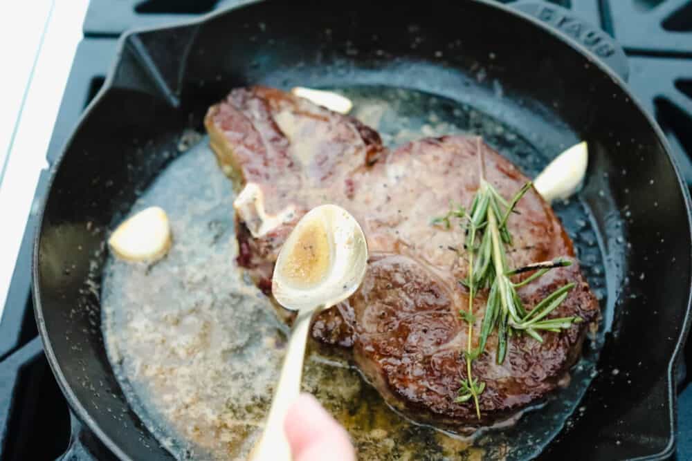 Achieving steakhouse-worthy flavors doesn’t have to be difficult! The ultimate ribeye steak is juicy, flavorful, and seared to perfection all in the comfort of your kitchen. Spooning butter over ribeye steak.