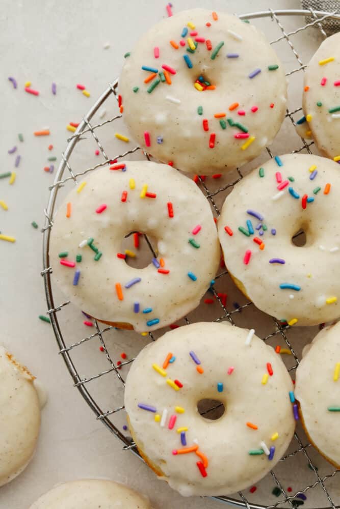 Cake donuts are rich and golden and take the word delicious to the next level!! The sweet taste completely melts in your mouth and the delicate frosting with sprinkles will leave you asking for more! Donuts on a cooling rack.