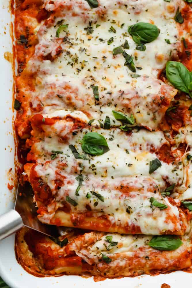 This manicotti is filled with 3 kinds of cheese and baked to absolute perfection! It's comfort food at its finest that everyone will go crazy over! It's definitely sure to please a large crowd! Manicotti being served with a serving spoon.