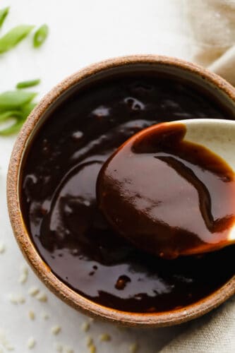 Rich, sweet, and salty, hoisin sauce is the perfect foundation for all of your Asian-inspired dishes. This homemade variation packs so much delicious flavor, you won't want store-bought again! Close-up of a spoon in hoisin sauce.