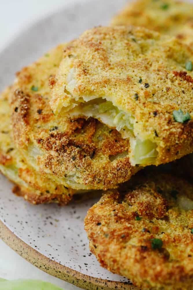 Air fryer fried green tomatoes are insanely delicious! Crispy on the outside and tender and juicy on the inside, these tomatoes will knock your socks off! A fried green tomato with a bite taken out of it.