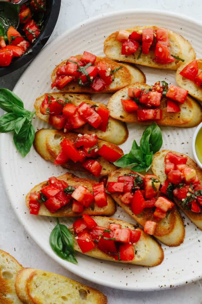 This easy, baked crostini is the best side to any Italian meal! They're golden, delicate pieces of heaven ready for your favorite toppings! Crostini pieces topped with tomato basil salad.