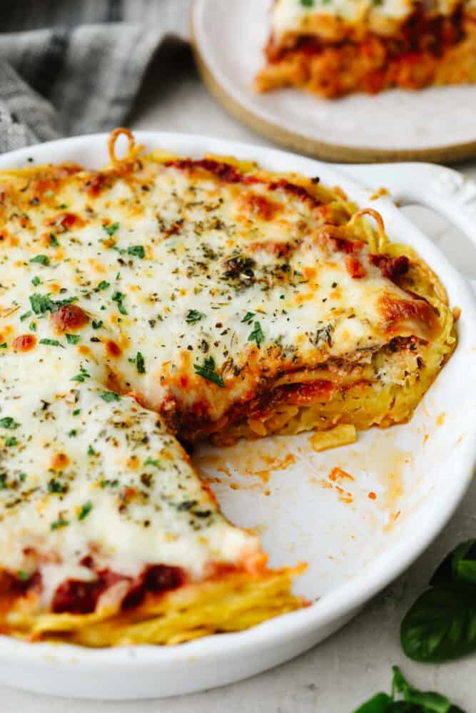 This tasty baked dish is super easy, cheesy, and flavorful! For adding a little Italian goodness to busy weeknights, spaghetti pie is the answer! A spaghetti pie with a slice taken out of it.