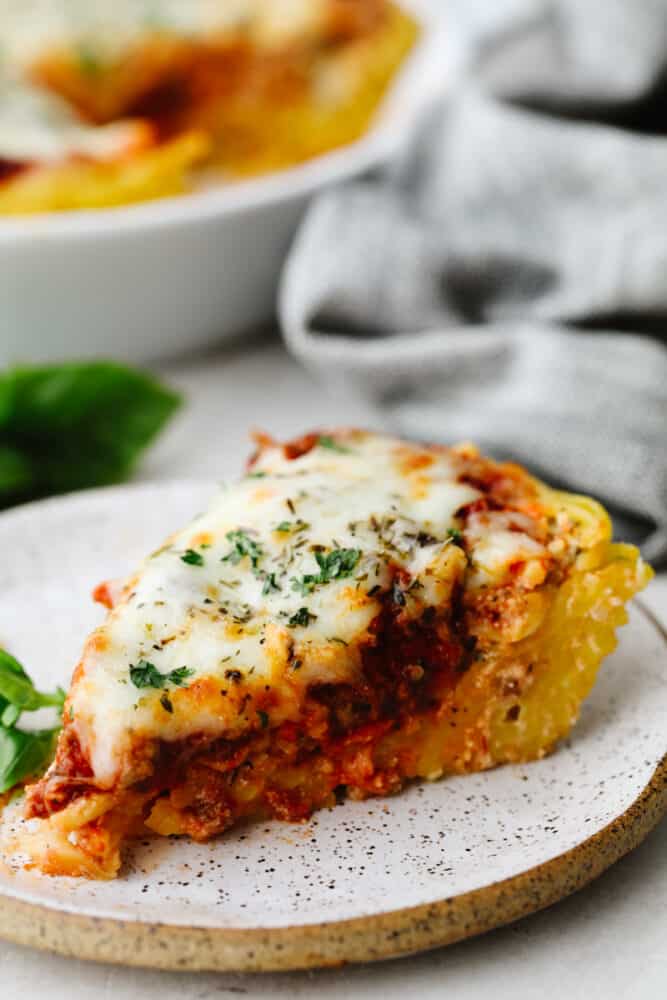 This tasty baked dish is super easy, cheesy, and flavorful! For adding a little Italian goodness to busy weeknights, spaghetti pie is the answer! A slice of spaghetti pie on a stoneware dish.