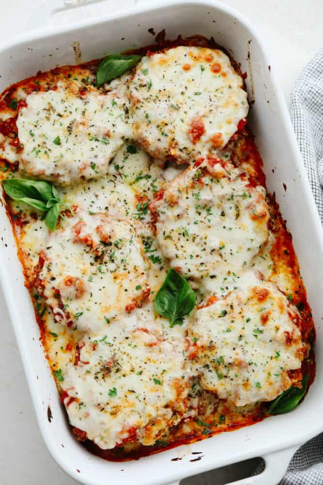Eggplant parmesan is a tangy, crispy, cheesy masterpiece! Delicious eggplant covered in a delightful mix of herbs and spices, this recipe will knock your socks off! Eggplant parmesan in a baking dish.
