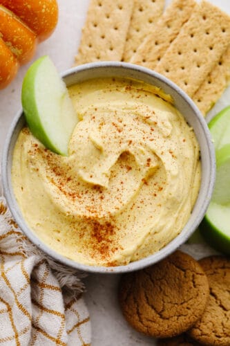 Pumpkin pie dip is deliciously light and fluffy! It has to creamiest texture and the spices bring that pumpkin pie flavor to life! It is something that your whole family will go crazy over! Pumpkin pie dip in a bowl with an apple slice in it.