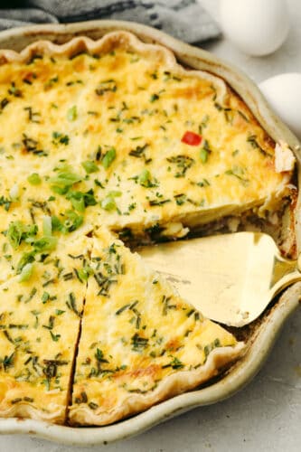 Creamy and custard-like, the best quiche starts with a basic recipe and has endless options for adding meat, vegetables, and herbs. This delicious staple recipe is perfect for breakfast, lunch, or dinner. A slice taken out of quiche.