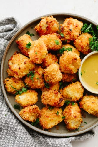 Air fryer chicken nuggets are absolute perfection! They are crispy on the outside, tender on the inside, and are just waiting to be dipped in any of your favorite sauces! Your family will go crazy over them! Chicken nuggets on a tray with honey mustard sauce.