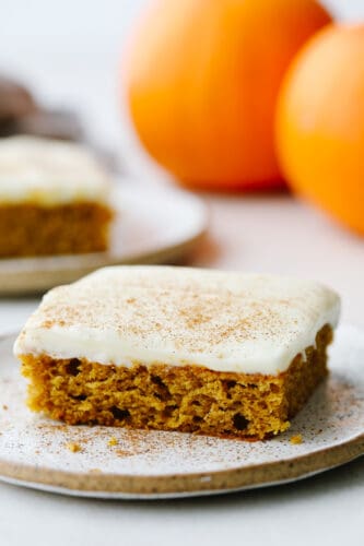 Pumpkin spice sheet cake not only tastes amazing but it feeds a crowd! Top it with some tangy cream cheese frosting and you have yourself a dessert to remember! A slice pf pumpkin spice sheet cake on a plate.