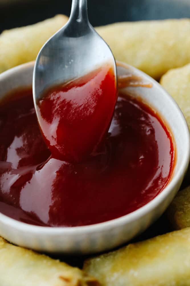 Sweet and sour sauce is perfectly tangy and zesty! It will add a delicious flavor to just about anything and will only take you about 10 minutes to make! A spoon being dipped in sweet and sour sauce.