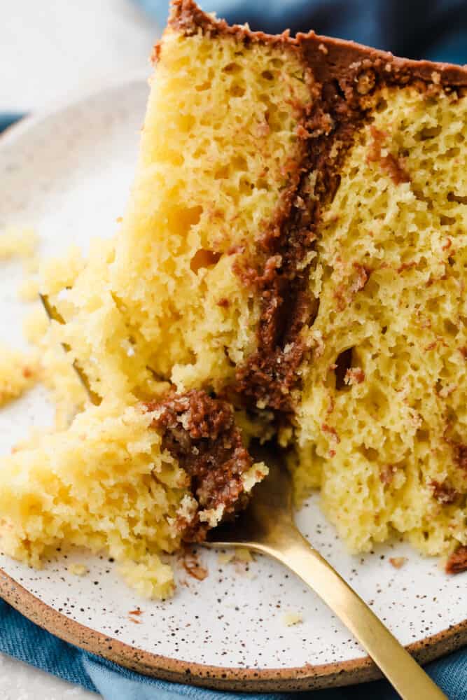 Yellow cake is a classic dish that we all know and love! Perfectly moist with a light and fluffy texture, it's a cake that we make ALL the time because everyone loves it! A slice of yellow cake with a fork taking a bite out of it.