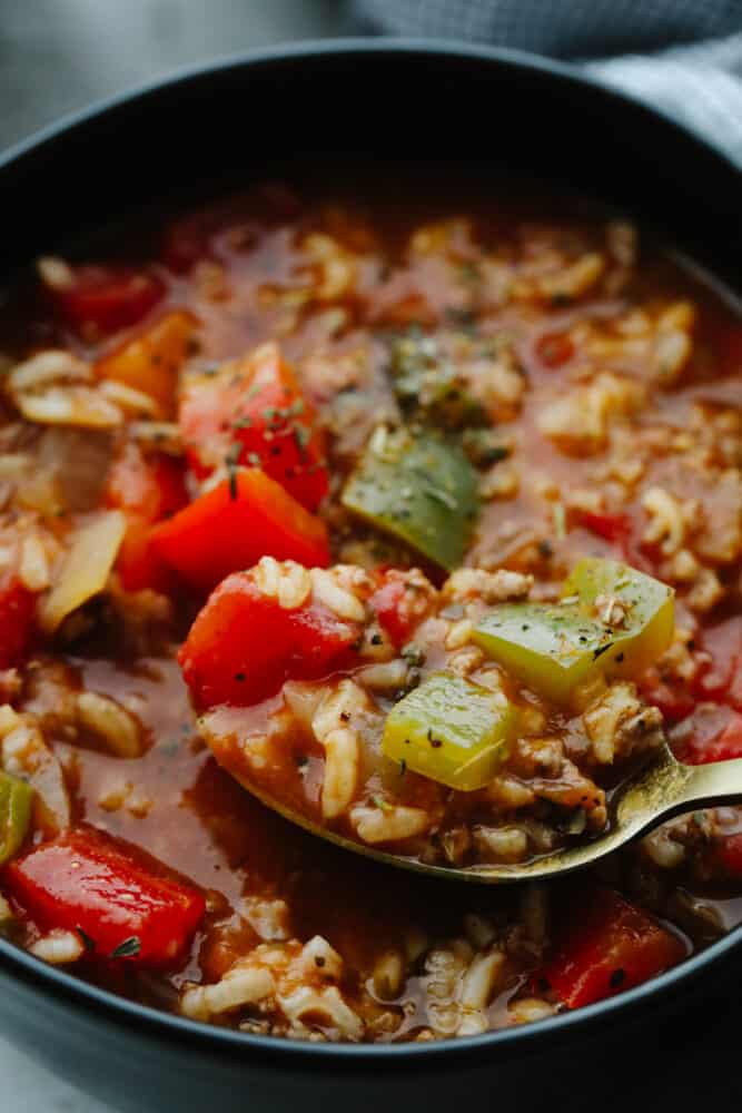 Stuffed pepper soup is delicious, hearty, and full of flavor! Filled with so many different ingredients, it's insanely good and will definitely fill your belly! Zoomed in picture of a spoon scooping up some stuffed pepper soup.