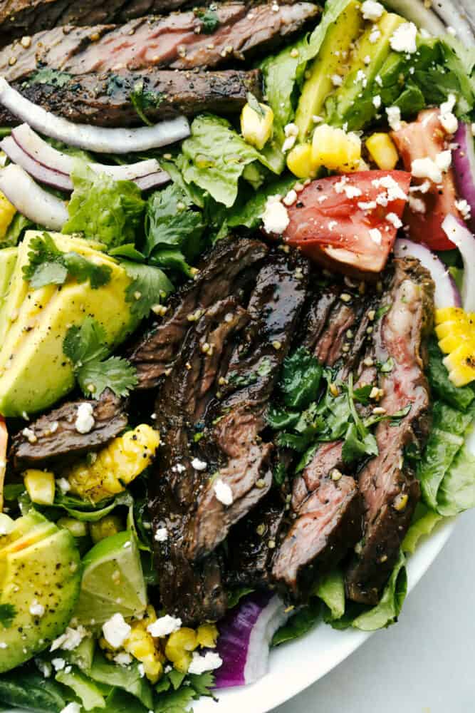 Juicy skirt steak, fresh veggies, and feta cheese- all tossed in a delicious tangy glaze. Steak salad with honey balsamic dressing is a mouthwatering meal infused with bold, savory flavor! Close-up of steak salad with honey balsamic dressing.