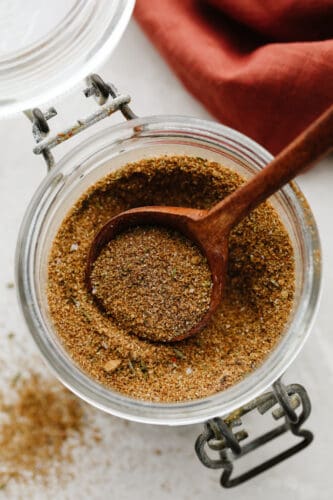 Jerk seasoning is the most deliciously sweet and savory blend of spices! It's simple to use and even more easy to make! You will have yourself a custom homemade seasoning in less than 5 minutes! Jerk seasoning in a jar with wooden spoon.