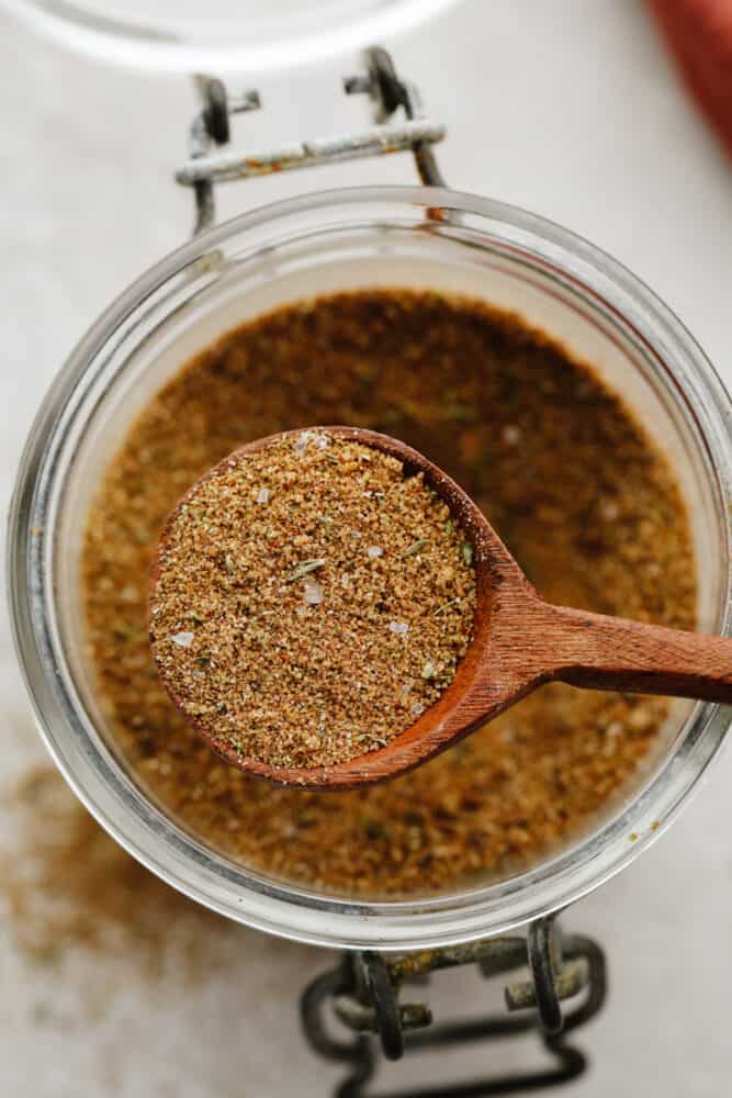 Jerk seasoning is the most deliciously sweet and savory blend of spices! It's simple to use and even more easy to make! You will have yourself a custom homemade seasoning in less than 5 minutes! Jerk seasoning being scooped with a wooden spoon.