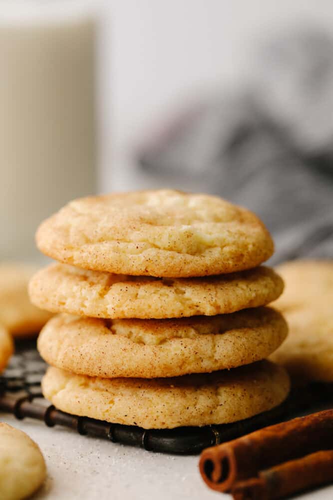 These snickerdoodle are delightfully soft and full of delicious cinnamon flavor! They are SOO GOOD and you won't be able to stop at just one! A stack of snickerdoodles on a cooling rack.