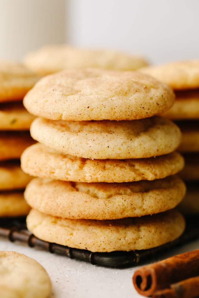 These snickerdoodle are delightfully soft and full of delicious cinnamon flavor! They are SOO GOOD and you won't be able to stop at just one! A stack of cookies on a cooling rack.