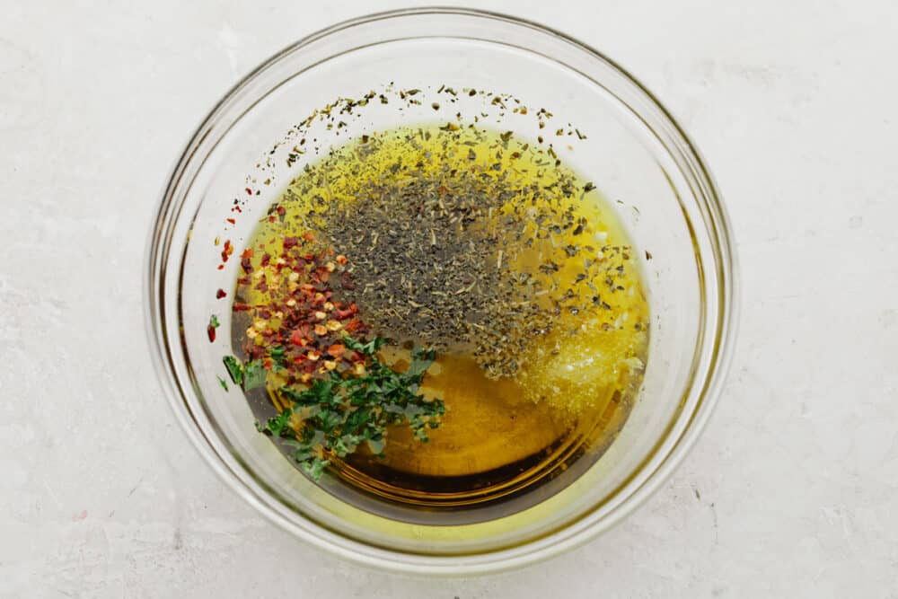 This olive oil bread dip is the absolute perfect appetizer! It has just the right blend of spices that taste SOO GOOD! It will definitely get a "WOW!" from all of your guests! a bowl with olive oil and spices being mixed into it.