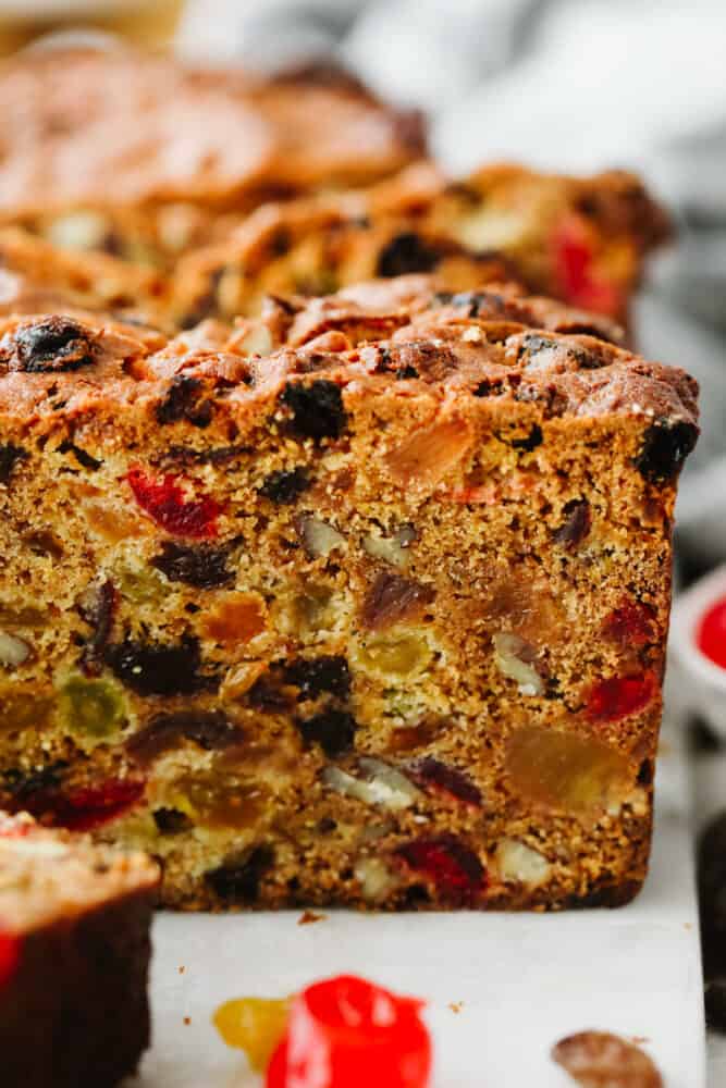 Fruit cake is a classic holiday dessert that you're going to love! With this recipe, you'll get a moist, flavorful treat every time! Closeup shot of a slice of fruitcake.