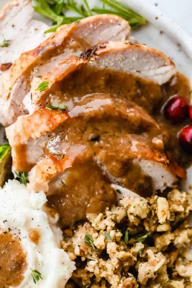 Turkey gravy is rich, thick, and creamy! This gravy takes less than 15 minutes to make! Once you drizzle it all over your turkey and potatoes, well, you will use this recipe for every holiday season! Gravy on top of turkey, potatoes and stuffing on a plate.
