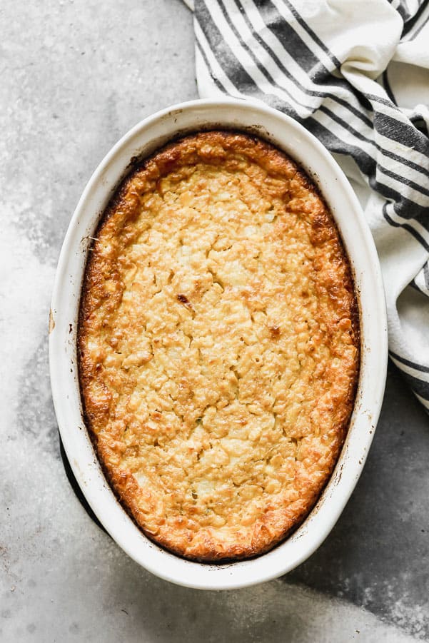 Corn Pudding is one of our favorite fall sides to serve alongside a roast chicken, hearty stew, or of course, turkey! Our version is ultra creamy, slightly sweet, with a hint of savory and packed with while corn kernels. Corn pudding in a white dish.