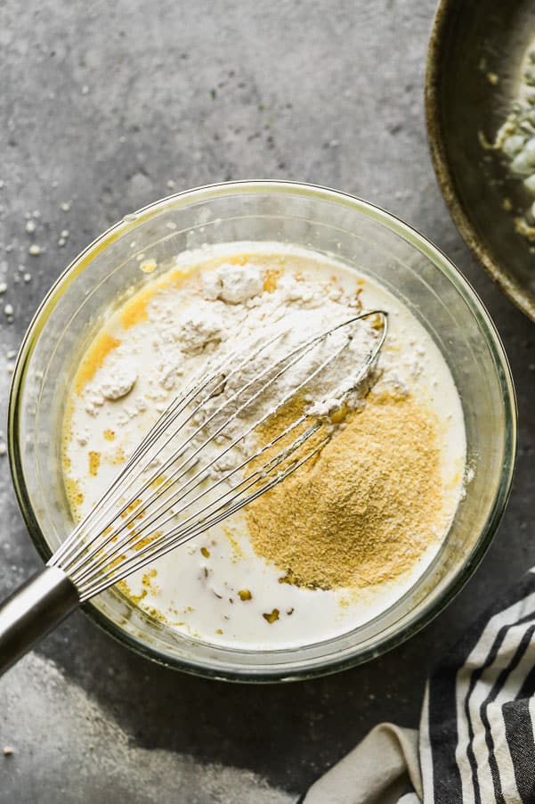 Corn Pudding is one of our favorite fall sides to serve alongside a roast chicken, hearty stew, or of course, turkey! Our version is ultra creamy, slightly sweet, with a hint of savory and packed with while corn kernels. Whisking ingredients into the glass bowl.