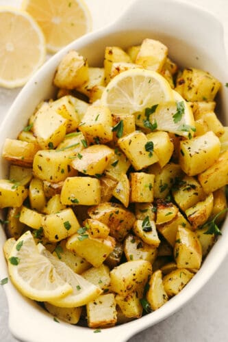 Roasted lemon potatoes are the perfect side dish for any of your meals! They have the best fresh taste that is SOO GOOD! Your friends and family will love them! Roasted potatoes in a serving dish garnished with seasonings and lemon slices.