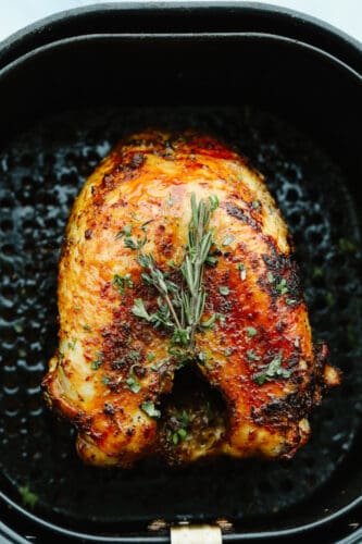 This juicy air fryer turkey is SOO GOOD and will have all of your guests asking for more! It's perfectly golden brown and dripping in flavor... You will never cook a turkey any other way again! A turkey in an air fryer with garnish.