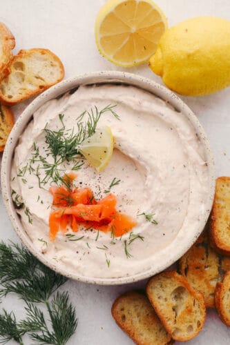 This smoked salmon dip is so creamy and delicious! With the smoked salmon flavor taking the stage followed by a hint of lemon and dill, this dip is SOO GOOD! Smoked salmon dip in a bowl with some garnish.
