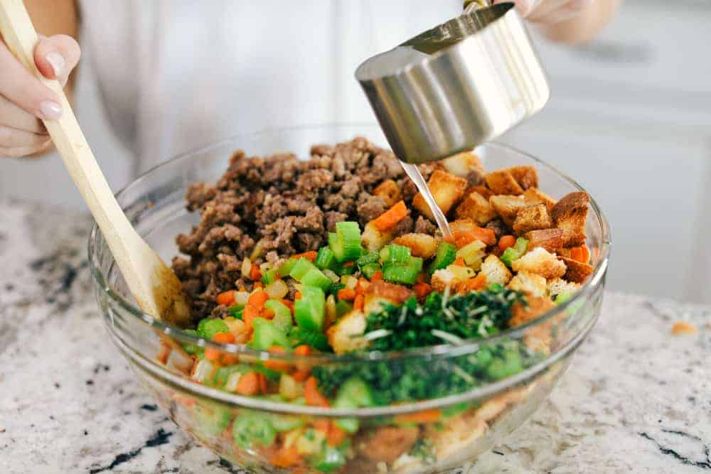 Grandma's sausage herb stuffing is a classic side dish! Baked bread, tender sausage, and crunchy vegetables are all mixed with flavorful herbs and baked until golden brown. It makes my mouth water just thinking about it! Vegetables and stuffing in a glass bowl.