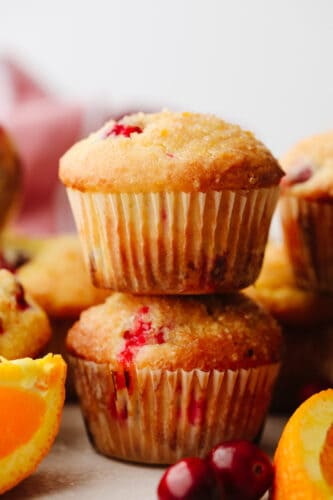 These sweet and zesty orange cranberry muffins are going to become your new favorite holiday breakfast! It's the perfect easy treat to start your day out with. 2 cranberry orange muffins stacked on top of each other.