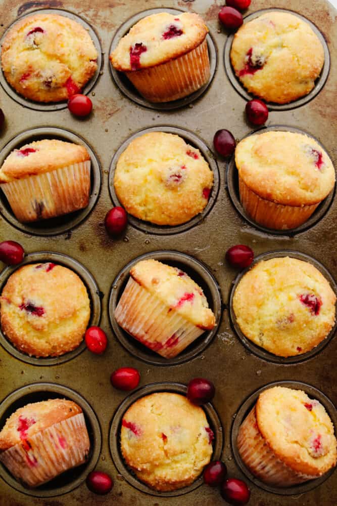 These sweet and zesty orange cranberry muffins are going to become your new favorite holiday breakfast! It's the perfect easy treat to start your day out with. Baked orange cranberry muffins in a muffin tin.