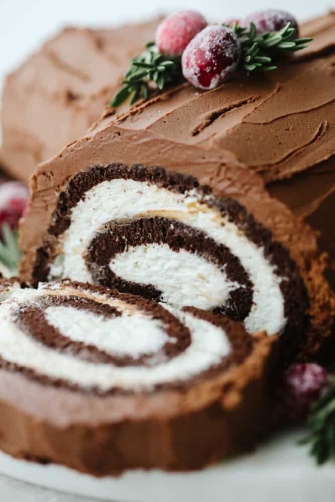 Show off your holiday spirit by baking this amazing yule log cake! A chocolate cake rolled with a cream cheese filling and topped with a chocolate ganache... It doesn't get much better than this! A close up of a yule log cake.