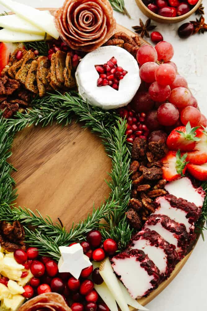 This Christmas wreath charcuterie board is the perfect festive touch to any holiday party! It's stunning and delicious! Plus, it's super easy to make and all of your guests will be so impressed! A close up of the side of the charcuterie board with nuts, cheeses and cranberries.