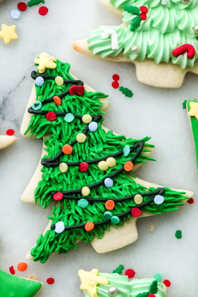 If you're wanting a dessert that is both festive and delicious, look no further! These Christmas tree sugar cookies will shine at any holiday party! Closeup of a Christmas tree sugar cookie with Christmas light detailing.