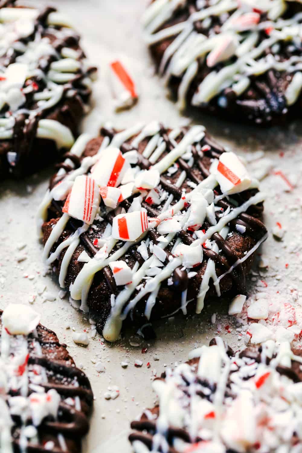 Triple chocolate peppermint cookies are soft and chewy cookies that get drizzled with white and dark chocolate. They are topped with crushed candy canes and are the perfect treat for the holidays! Triple chocolate peppermint cookies close up.
