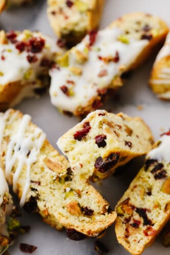 Cranberry pistachio biscotti are the tangy, nutty biscuits of your dreams! Topped off with a delicate white chocolate drizzle, these delicious treats will shine at all of your holiday get-togethers! Closeup of cranberry pistachio biscotti.