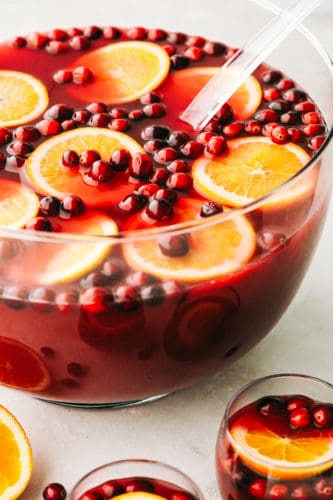 This easy Christmas punch is delicious and so festive! It's the perfect punch to serve at your next gathering. It's for all ages, young and old! Christmas punch with cranberries and orange slices.