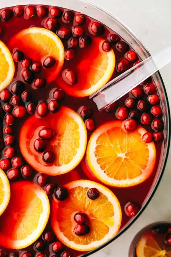 This easy Christmas punch is delicious and so festive! It's the perfect punch to serve at your next gathering... It's for all ages, young and old! A punch bowl filled with cranberry orange punch that's garnished with orange slices and cranberries.