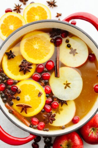 This traditional English drink is the perfect combination of fruit and spice! Wassail mixes up in a snap and is the perfect holiday crowd-pleaser! Homemade wassail in a punch bowl garnished with apples, oranges, cranberries, and spice.