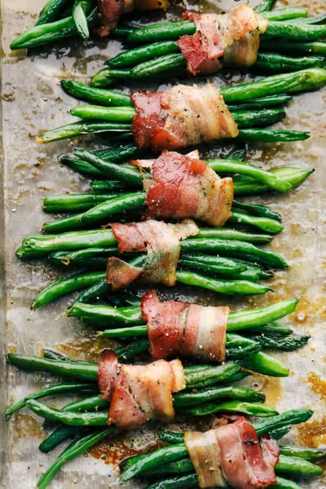 These green bean bundles are the ultimate side dish! Crispy bacon wrapped around succulent green beans will be your new tradition this holiday season! Beans wrapped in bacon, cooked and ready to eat.