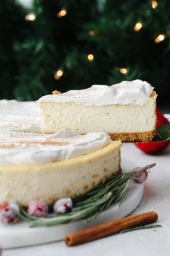 This eggnog cheesecake is SOO GOOD. It's creamy and melts in your mouth! That classic eggnog taste makes it the best dessert for the holiday season! A slice of cheesecake being taken out.