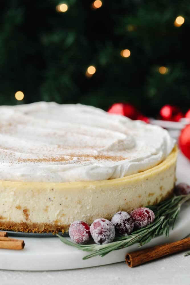 This eggnog cheesecake is SOO GOOD. It's creamy and melts in your mouth! That classic eggnog taste makes it the best dessert for the holiday season! A zoomed in view of the side of a whole eggnog cheesecake.