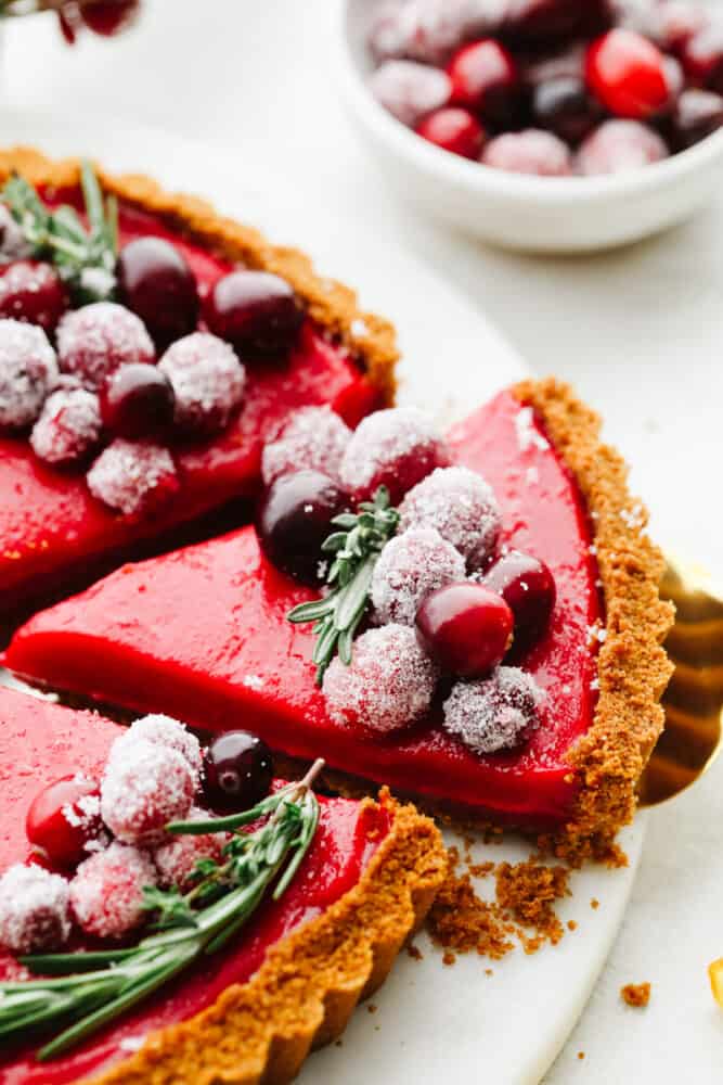 With a smooth tangy filling and Biscoff crust, this cranberry curd tart is a must-make for the holidays. It's as delicious as it is beautiful! Taking a slice of cranberry curd tart.