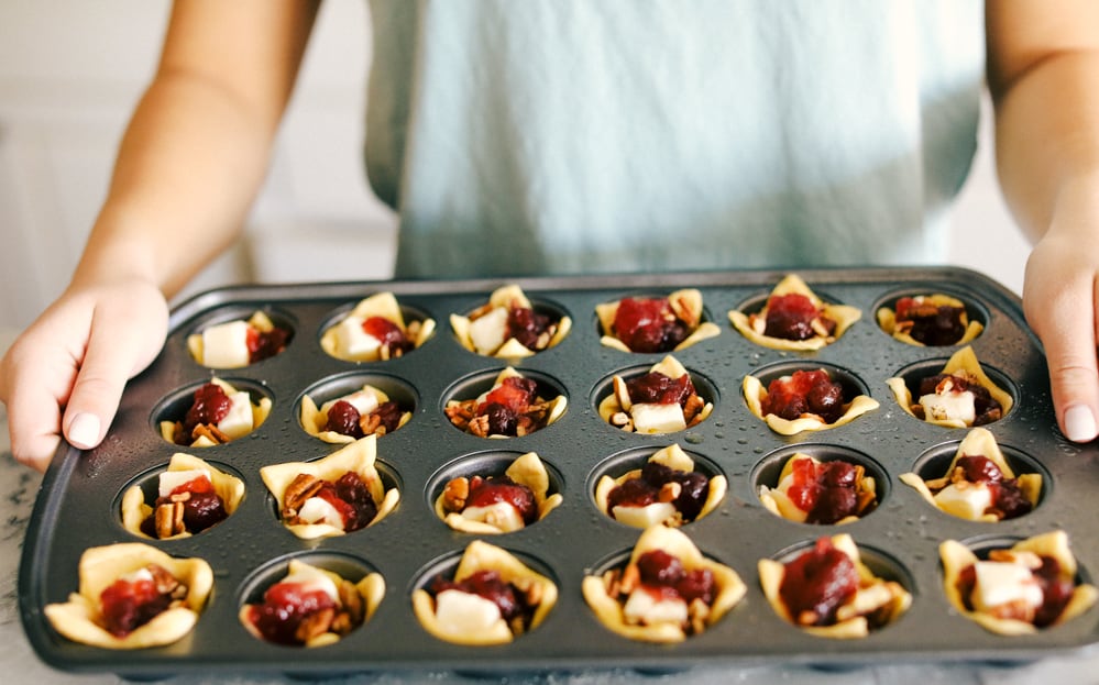 Cranberry pecan brie bites are such an amazing appetizer! It has layered pecans, soft brie, and a dollop of cranberry sauce all cupped in a golden brown, flaky crescent roll! Cranberry pecan brie bites in a muffin tin.