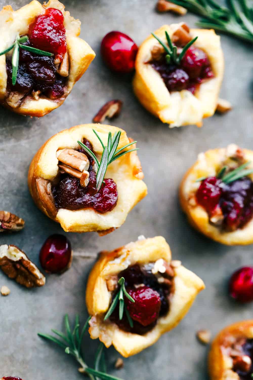Cranberry pecan brie bites are such an amazing appetizer! It has layered pecans, soft brie, and a dollop of cranberry sauce all cupped in a golden brown, flaky crescent roll! Baked cranberry pecan brie bites on a serving platter.
