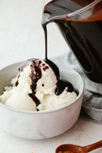 This homemade chocolate sauce has the perfect chocolate flavor and the smooth texture is to die for. It goes on just about anything and is so simple to make! Chocolate sauce being poured onto some vanilla ice cream.