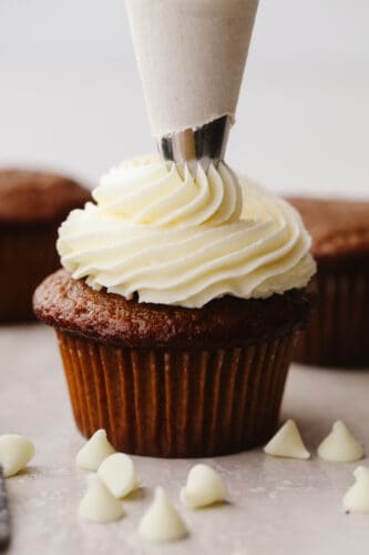 This smooth and creamy white chocolate buttercream is perfect for all of your favorite cakes and cupcakes! You'll want this silky frosting on everything! A chocolate cupcake piped with white chocolate buttercream.