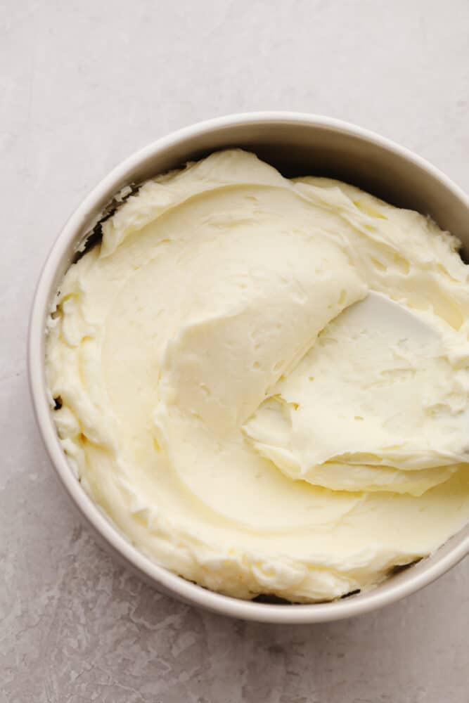 This smooth and creamy white chocolate buttercream is perfect for all of your favorite cakes and cupcakes! You'll want this silky frosting on everything! White chocolate buttercream frosting in a white bowl.