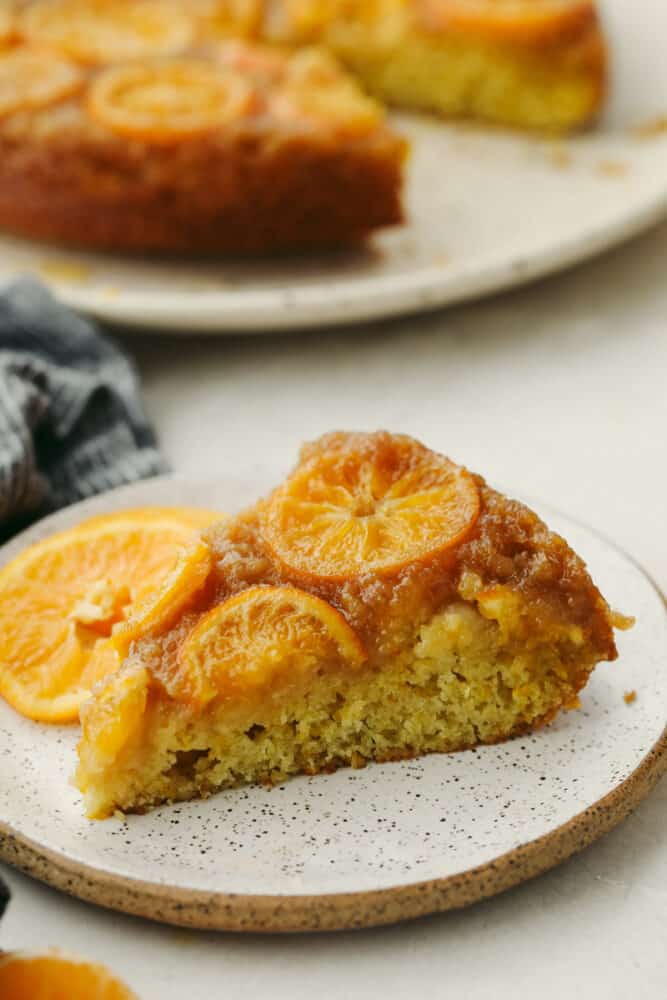 Soft and moist with a sweet juicy flavor, this is one citrus dessert you won't want to miss! Clementine cake is a must-try for the holidays! A slice of clementine cake on a white plate.